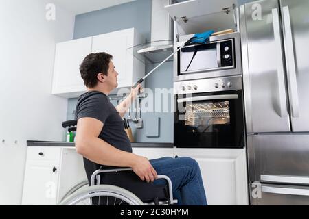 L'Uomo Disabile Usando Lo Strumento Grabber Per Afferrare I Potolids In Cucina Foto Stock