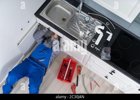 Lavoratore Sdraiato A Pavimento Riparazione Cucina Lavello Con Chiave Regolabile Foto Stock