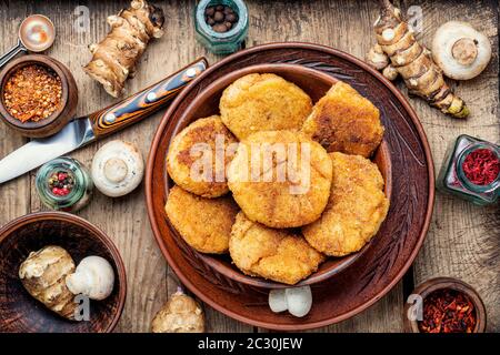 Cotolette di verdure fritte con topinambur e funghi. Rissole su tavola di legno. Cibo Sano Foto Stock