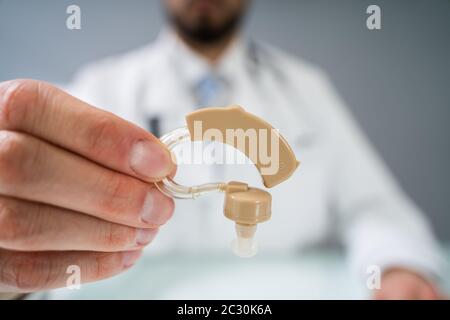 Dispositivo Di Ausilio All'Udito Di Doctor Holding In Clinic Foto Stock