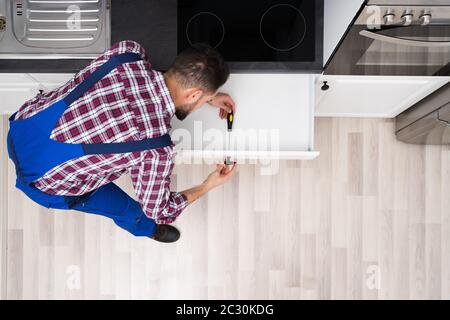 Close-up di un giovane maschio falegname di installare il cassetto con il cacciavite Foto Stock