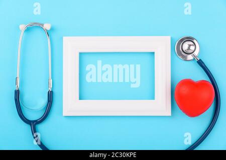 Concetto del giorno del medico, vista dall'alto a disposizione piatta, stetoscopio con diagnosi della cornice fotografica della malattia di cuore sullo sfondo blu con spazio di copia per il testo Foto Stock