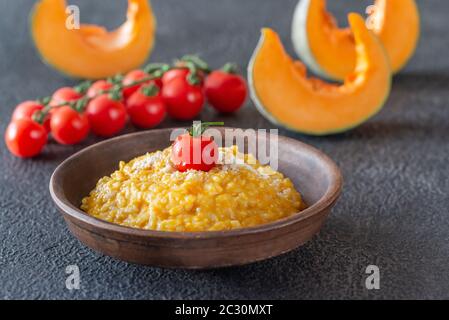 Porzione di risotto alla zucca decorata con pomodoro ciliegino Foto Stock