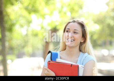 Vista frontale di uno studente felice che pensa di guardare di lato in un parco Foto Stock