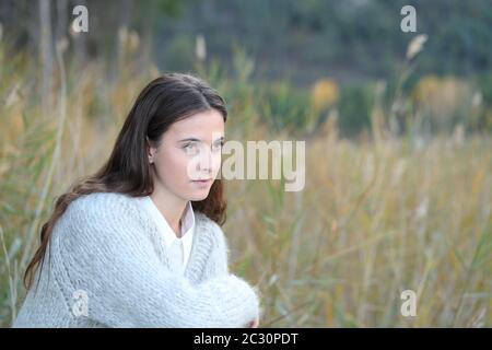 Ritratto di una ragazza adolescente seria pensante penosa che guarda via su un campo Foto Stock