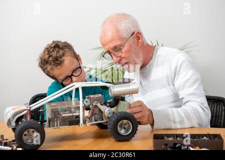 nonno e figlio ragazzino che riparano una macchina radio-controllata modello a casa Foto Stock