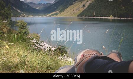 Hiker prendere una pausa seduto vicino al lago di Oule nella valle di Aure in Haute-Bigorre nel dipartimento degli alti Pirenei in Francia Foto Stock