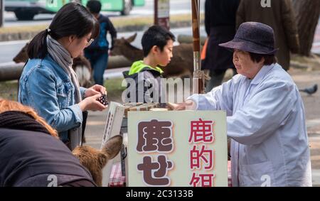 Vecchia signora giapponese che vende biscotti di cervo ai turisti a Nara Park, Giappone Foto Stock