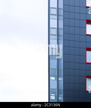 Angolo di un edificio con molte finestre contro un cielo bianco. Concetto di costruzione moderna. Foto Stock