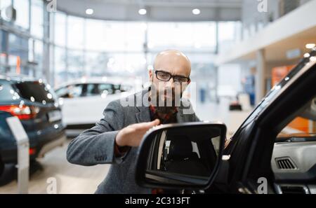 L'uomo controlla la verniciatura del nuovo pick-up nel concessionario di automobili. Cliente nello showroom dei veicoli, uomo che acquista il trasporto, commercio del commerciante dell'automobile Foto Stock