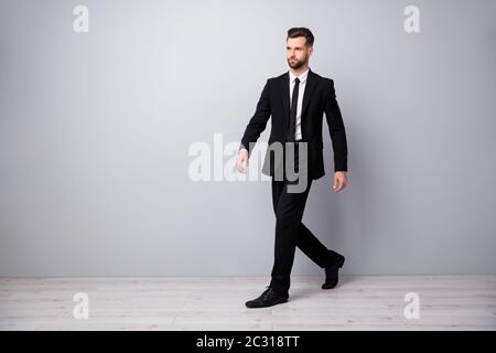 Foto laterale profilo full size di un bell'uomo lavoratore economista va a piedi al posto di lavoro riunione indossare pantaloni alla moda isolato sopra colore grigio Foto Stock