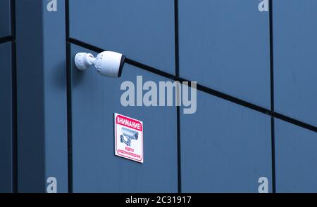 Le telecamere TVCC sono installate sulla facciata di un edificio grigio per uffici. Concetto di sicurezza e avvertenza. Foto Stock