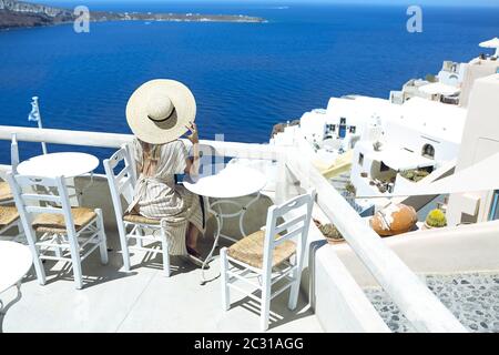 Giovane donna in un abito bianco e cappello di paglia, a piedi nella città di Oia, isola di Santorini, Grecia Foto Stock