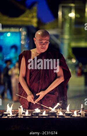 Ritratto di monaco buddista accende una candela Foto Stock