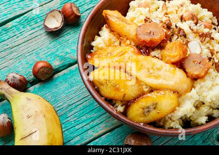 Porridge di miglio dolce con banane e noci in ciotola di ceramica. Foto Stock