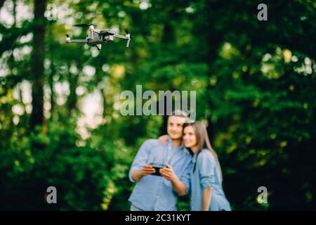 Ritratto di uomo e donna sta facendo funzionare il drone dal telecomando nel parco. L'uomo e la donna giocano con il quadricopter all'aperto. Foto Stock