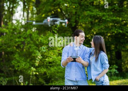 Ritratto di uomo e donna sta facendo funzionare il drone dal telecomando nel parco. L'uomo e la donna giocano con il quadricopter all'aperto. Foto Stock