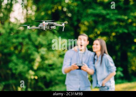 Ritratto di uomo e donna sta facendo funzionare il drone dal telecomando nel parco. L'uomo e la donna giocano con il quadricopter all'aperto. Foto Stock