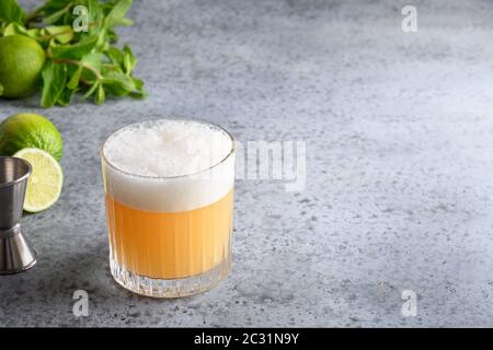 Cocktail Pisco Sour. Wiskey con lime, albume d'uovo, miele su grigio. Primo piano. Foto Stock