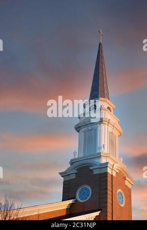 Una chiesa battista steeple rising in un blu chiaro mattina presto sky con mezza luna in background Foto Stock