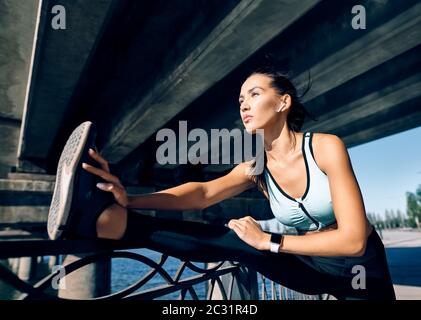 Donna sportiva che allunga le gambe per riscaldarsi prima di allenarsi Foto Stock