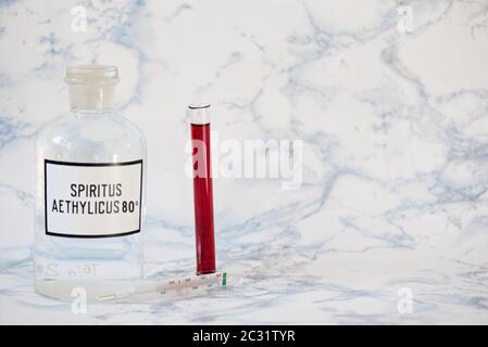 Etanolo in bottiglia e analisi del sangue sul tavolo. Concetto di coronavirus Foto Stock