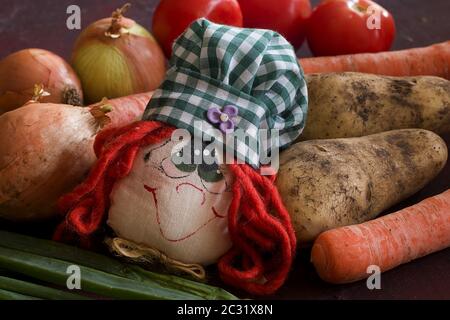 alcune verdure e una bambola di un paese in un tavolo da cucina Foto Stock