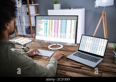Close-up di una imprenditrice la mano esaminando un foglio di calcolo sul computer portatile in ufficio Foto Stock