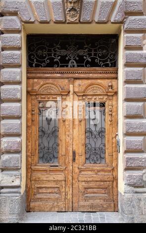 Porta doppia in legno d'epoca con pannelli incorniciati e antichi tralicci in metallo riccamente decorati Foto Stock