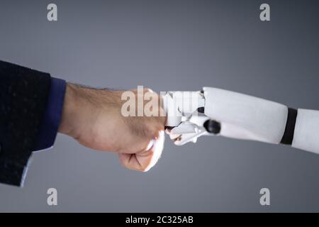 Il robot e la mano umana facendo Fist Bump su sfondo grigio Foto Stock