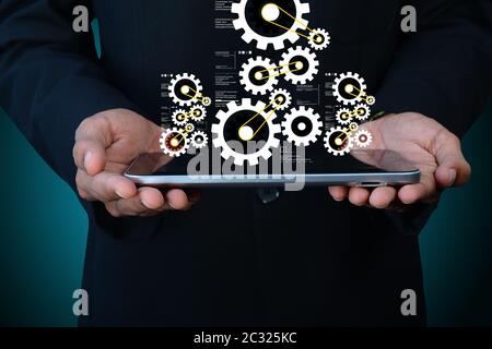 Tavoletta digitale in mano e ingranaggi Foto Stock
