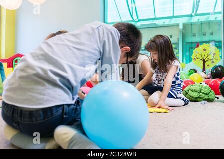 Gruppo di bambini prescolastica che circondano il loro insegnante esperto durante un'attività educativa in classe di un moderno asilo Foto Stock