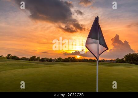 Cielo di tramonto sul fairway di un campo da golf in Texas con una bandiera di golf in primo piano Foto Stock