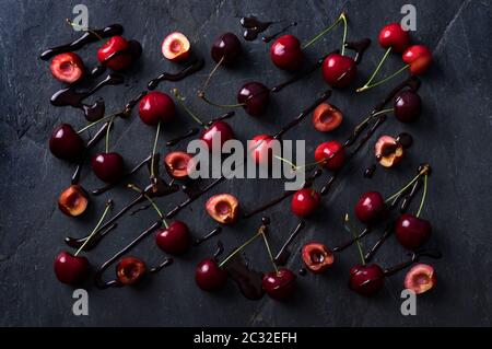 Ciliegie e cioccolato su pietra scura superficie collage di disegno alimentare Foto Stock