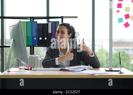 Una donna d'affari sembra molto felice dopo aver visto i profitti dall'investimento via e-mail. Entrambe le mani alzarono i pollici e sorrisero. Ha ottenuto un grande Foto Stock