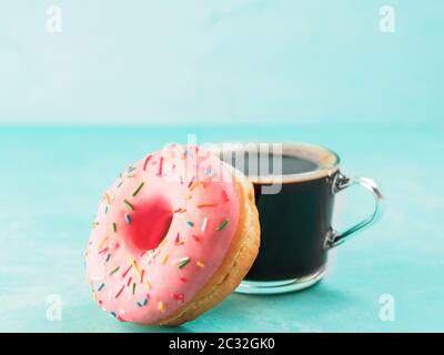 Rosa a ciambella e del caffè su sfondo blu , spazio di copia Foto Stock