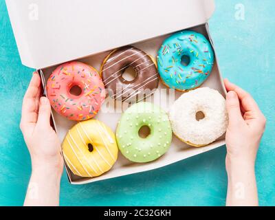 Le mani della scatola di contenimento con ciambelle Foto Stock