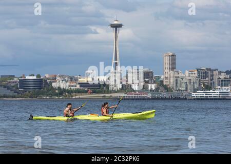 Una giovane coppia pagaia in un kayak tandem all'ombra dello Space Needle in un pomeriggio soleggiato a Seattle, Washington. Foto Stock