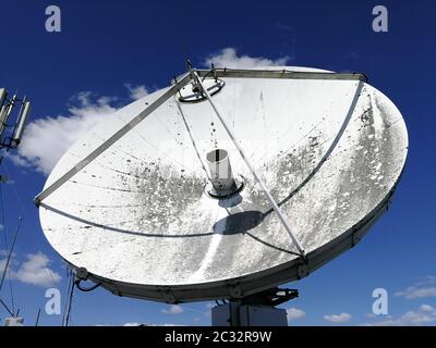 Enorme antenna parabolica satellite retrò sul tetto per il collegamento ad alta velocità di Internet di fronte al cielo blu Foto Stock