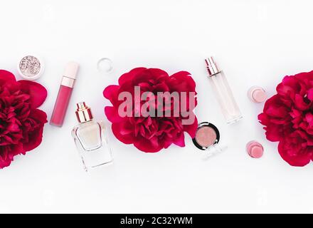 Modello di design alla moda con layout di cosmetici rosa decorato con peonie rosse di vino su sfondo bianco. Stile di posa piatto. Spazio di copia. Mockup per il vostro des Foto Stock