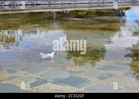 Barco de papel flotando sobre el agua de un estanque Foto Stock