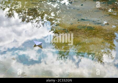 Barco de papel flotando sobre el agua de un estanque Foto Stock