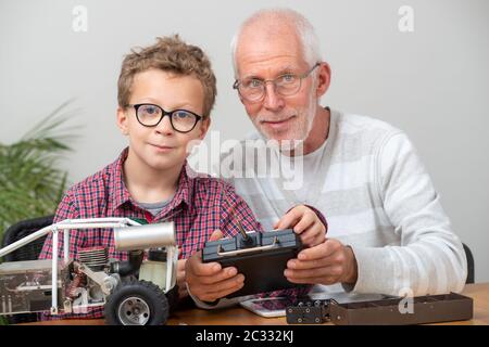 nonno e figlio ragazzino che riparano a casa un modello di auto radiocomandata Foto Stock