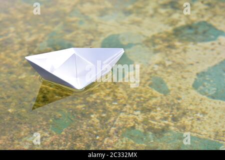 Barco de papel flotando sobre el agua de un estanque Foto Stock