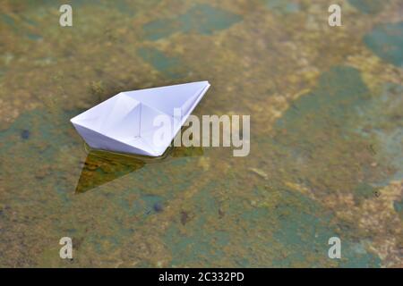 Barco de papel flotando sobre el agua de un estanque Foto Stock