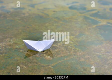 Barco de papel flotando sobre el agua de un estanque Foto Stock