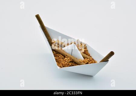 Barco de papel cargado de tabaco sobre fondo blanco Foto Stock