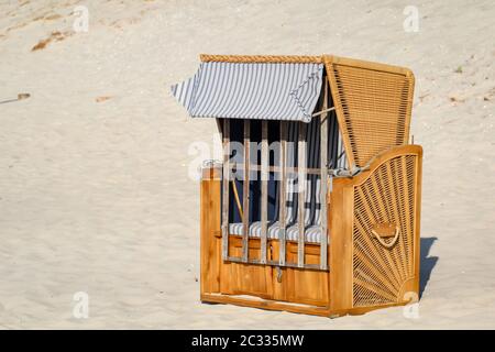 Una sedia da spiaggia chiusa si trova solo sulla spiaggia del Mar Baltico Foto Stock