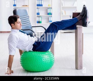 Giovane imprenditore facendo sport stretching al lavoro Foto Stock