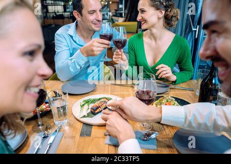 Due coppie che gustano cibo e bevande in un ristorante elegante Foto Stock